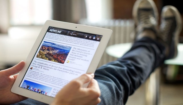 Hombre-con-los-pies-puestos-en-una-mesa-leyendo-unas-noticias-en-su-tablet